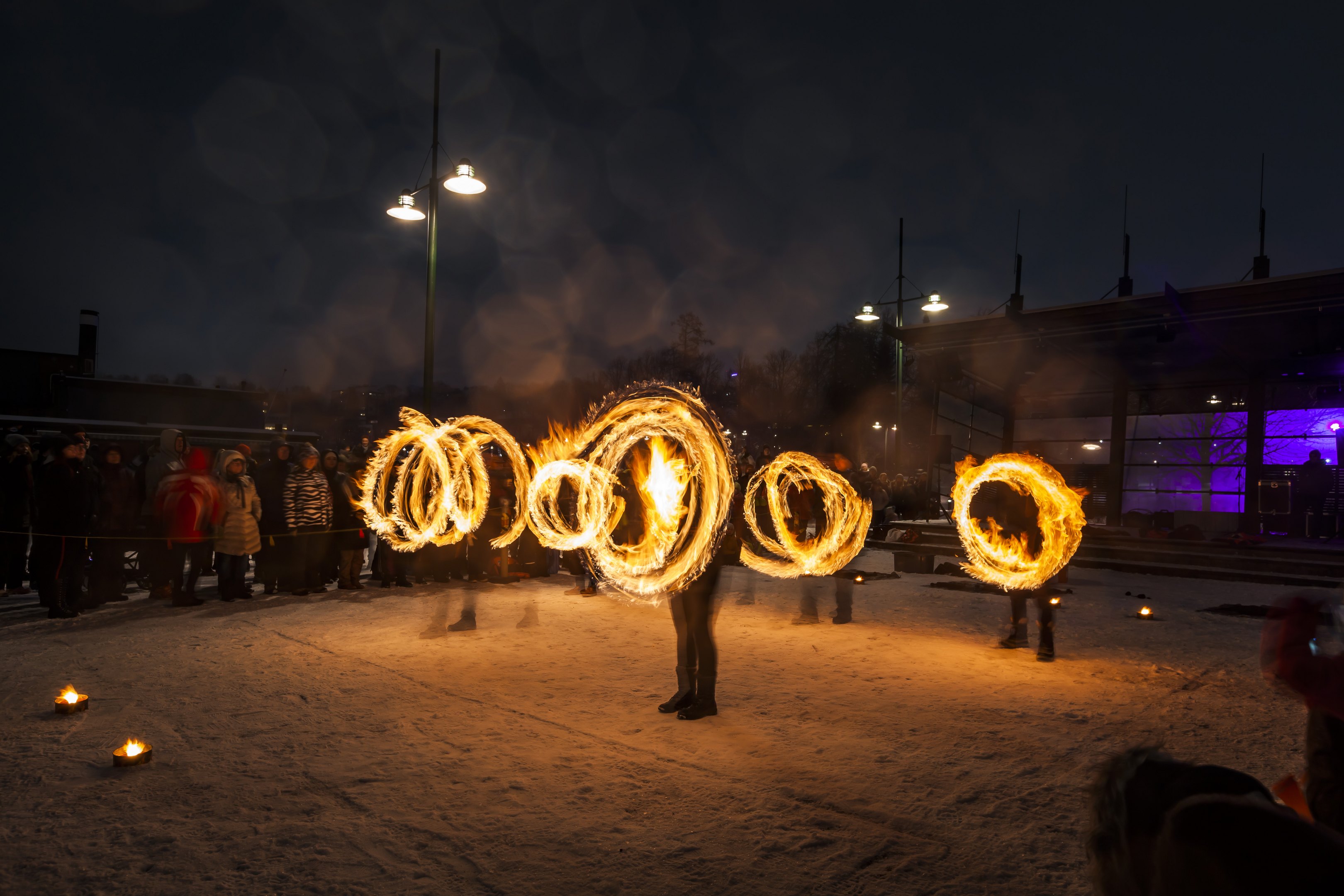 Kuva syystapahtumasta, jossa tulitaiteilijat tekevät ilmaan tulirinkuloita. Yleisö katsoo sivummalla. 